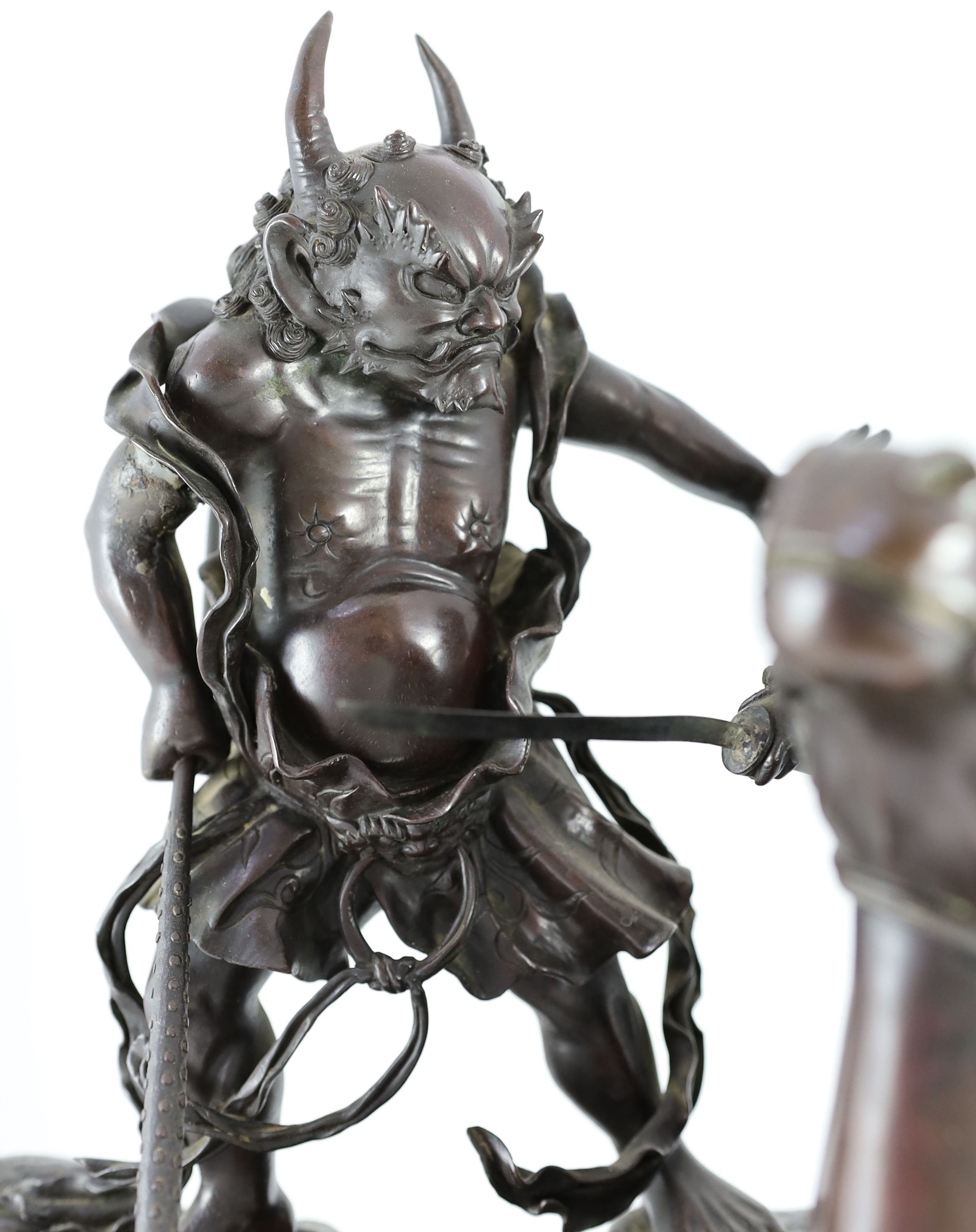 An impressive Japanese bronze group of an oni attacking a Samurai on horseback, Meiji period, 58cm high 49.5cm wide